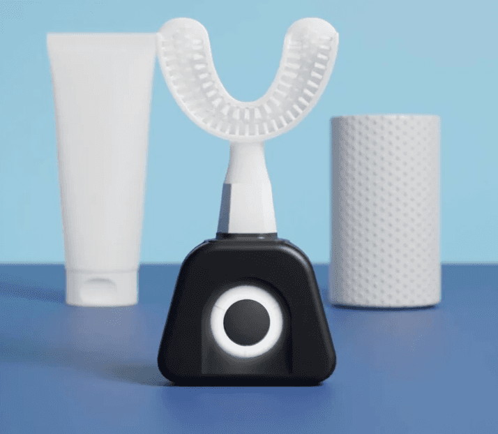 Premium Y-Sonic Electric Toothbrush (4 Modes) with U-shaped brush head on black base, shown with toothpaste and accessories in oral care setup.