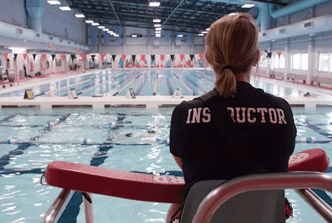 Lifeguard instructor overseeing a swim training session at an indoor pool during the Lifeguard Instructor Certification Course. Ideal for lifeguard training services.
