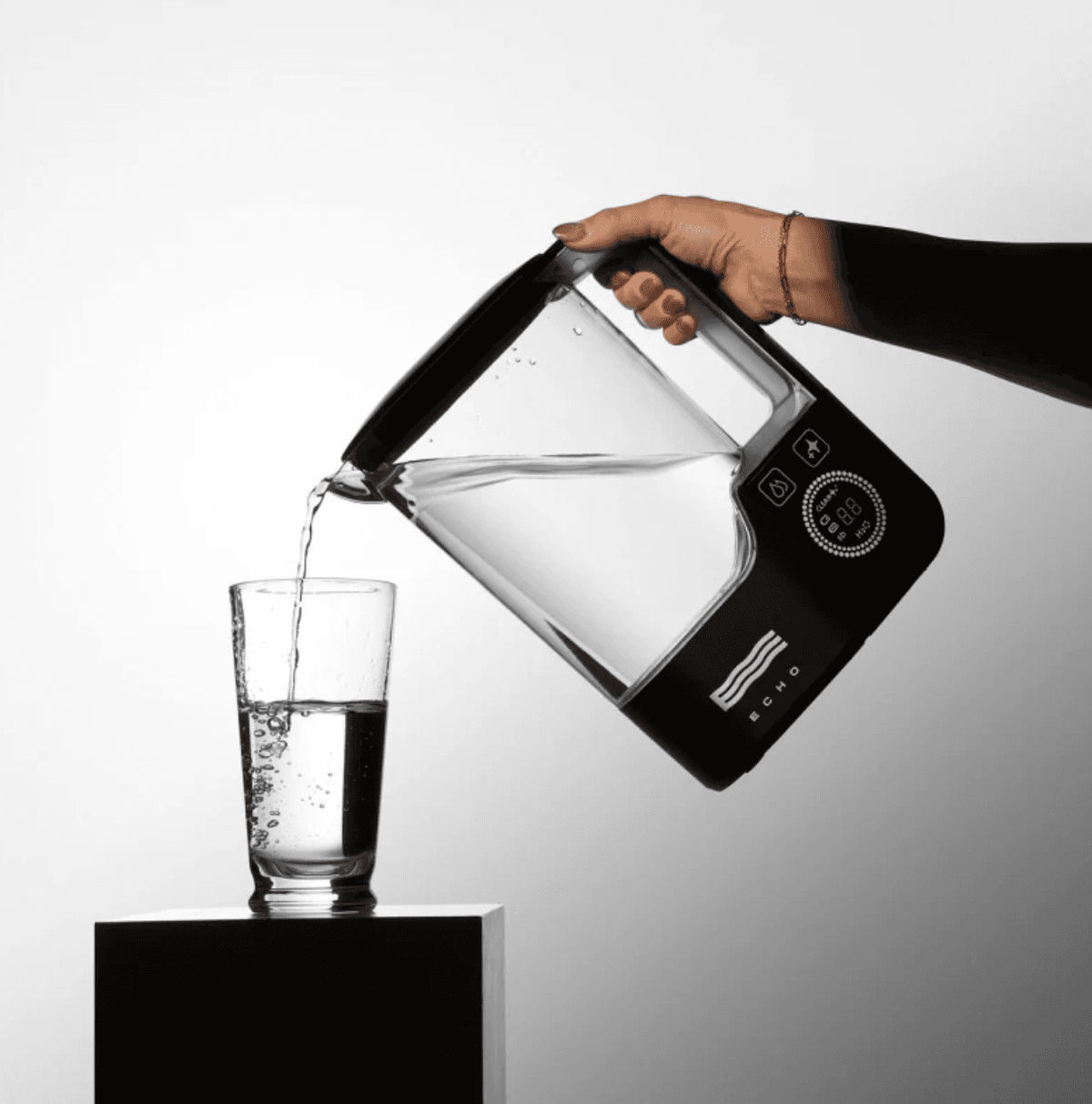 Hand pouring hydrogen-enriched water from the Hydrogen Water Pitcher into a glass, promoting sustainable and healthy hydration habits.